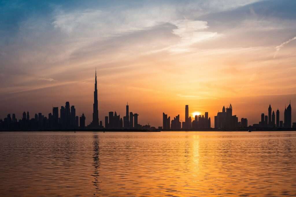 Enchanting view of Dubai's skyscrapers at sunset with the iconic Burj Khalifa outlined against the vivid sky.